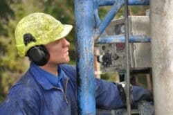 Drilling crewman studies cable as it lowers into the well