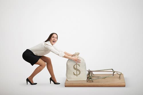 Woman holding onto a stack of money placed on a mouse trap