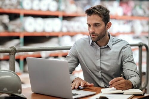 Warehouse manager taking notes and checking orders with a laptop Customer Order