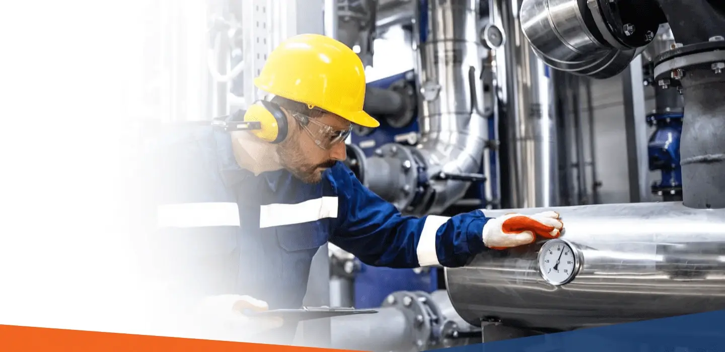 Industrial worker in safety gear inspecting machinery and monitoring pressure levels.